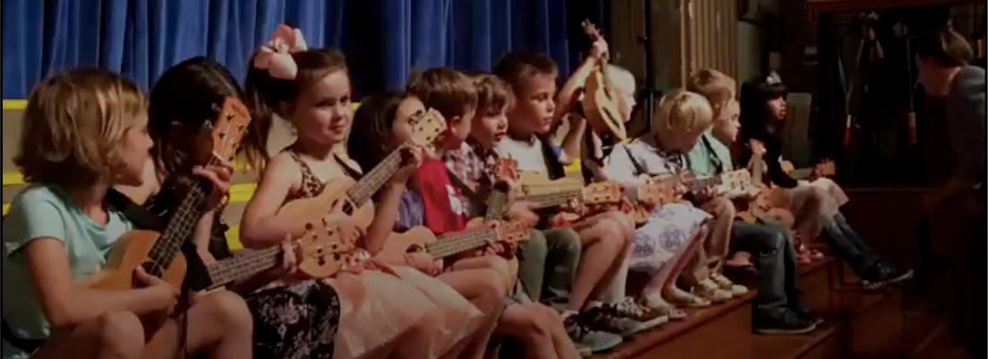 Students on stage playing with a guitar