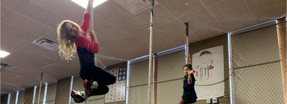 2 students hanging on ropes in the gym